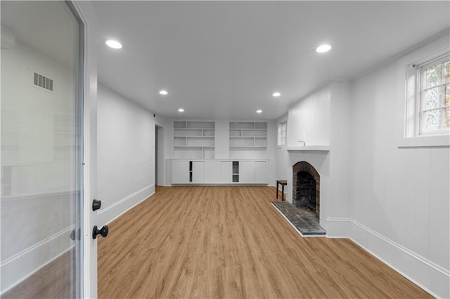 unfurnished living room with light wood-style flooring, recessed lighting, a fireplace, baseboards, and built in features