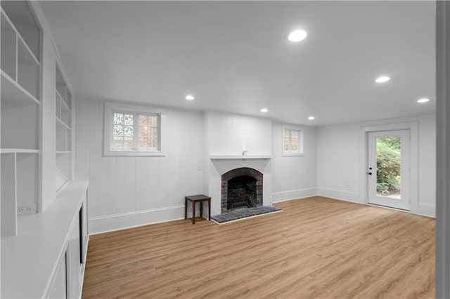 unfurnished living room with recessed lighting, a brick fireplace, baseboards, and light wood-type flooring