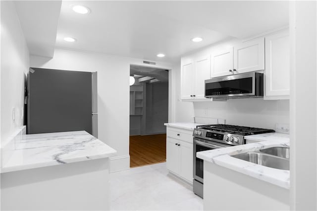 kitchen with stainless steel appliances, white cabinetry, recessed lighting, and light stone countertops