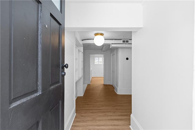 corridor with baseboards and light wood-type flooring