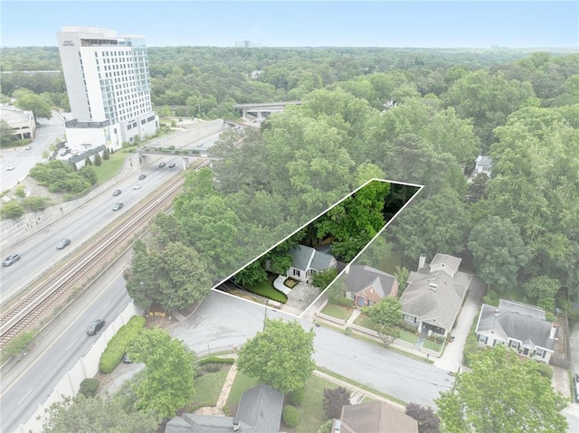 aerial view of property and surrounding area featuring a heavily wooded area, property parcel outlined, and a main thoroughfare