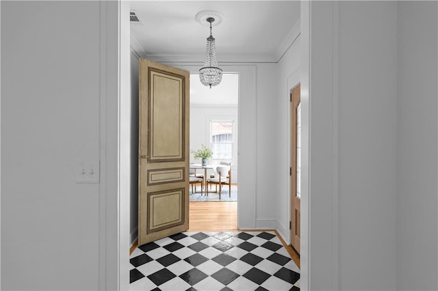 foyer featuring light flooring, crown molding, a chandelier, and baseboards