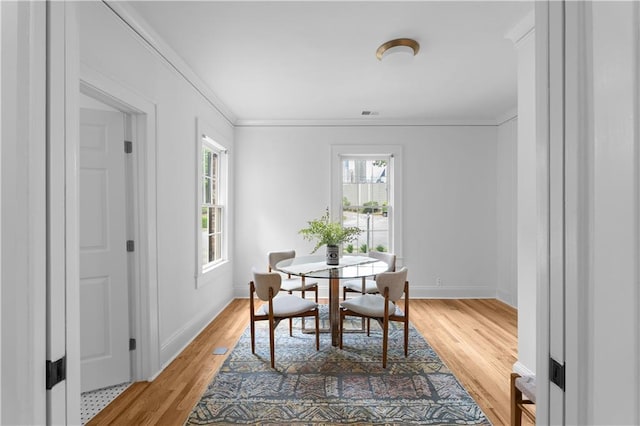 dining space featuring plenty of natural light, light wood finished floors, ornamental molding, and baseboards