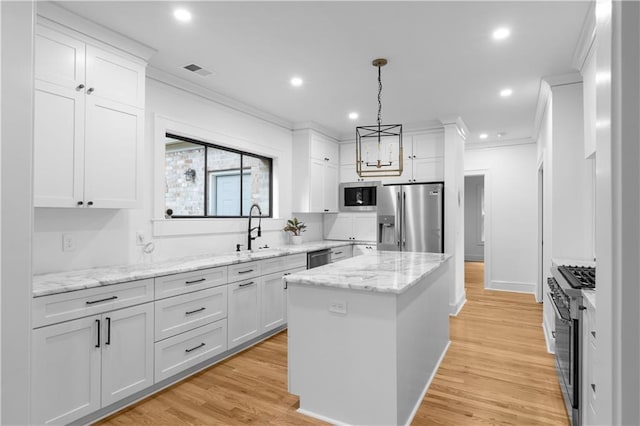 kitchen with appliances with stainless steel finishes, a sink, crown molding, a kitchen island, and white cabinetry