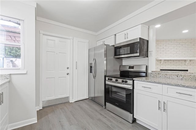 935 Bobcat Ct SE, Marietta, GA 30067 - kitchen featuring appliances with stainless steel finishes, light wood-type flooring, white cabinetry, light stone counters, and crown molding