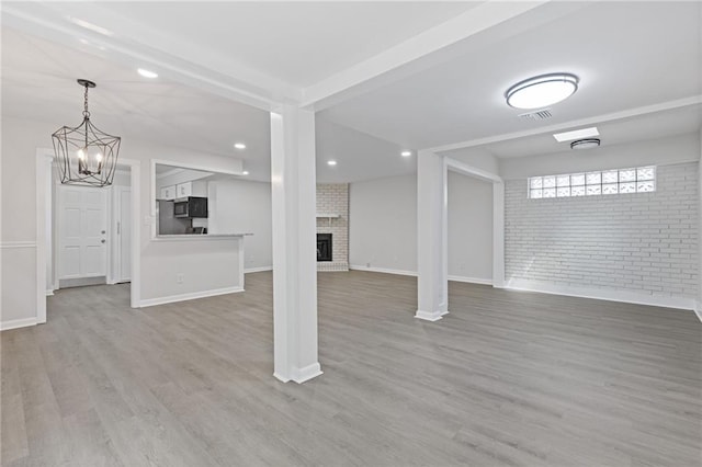 935 Bobcat Ct SE, Marietta, GA 30067 - basement featuring brick wall, wood finished floors, a chandelier, a fireplace, and recessed lighting