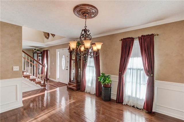 foyer entrance with ornamental molding, dark hardwood / wood-style floors, and a chandelier