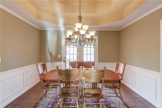 dining space featuring dark hardwood / wood-style flooring, a tray ceiling, crown molding, and a chandelier