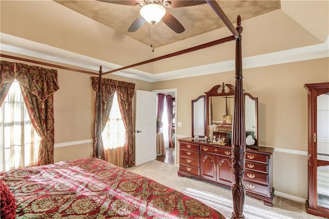 bedroom featuring a tray ceiling, light colored carpet, and ceiling fan