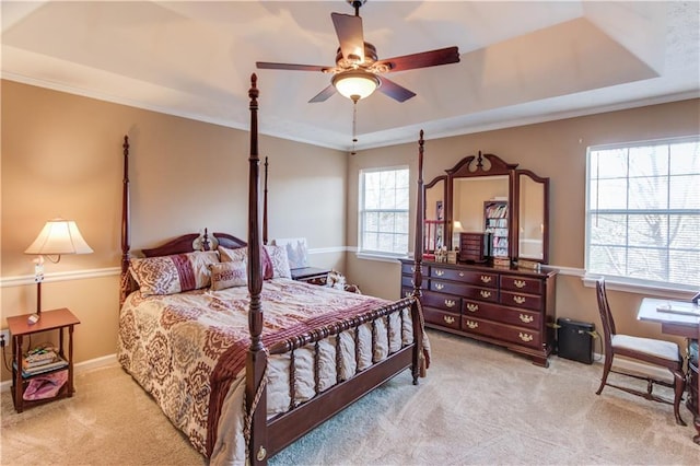 carpeted bedroom with a raised ceiling, ornamental molding, and ceiling fan