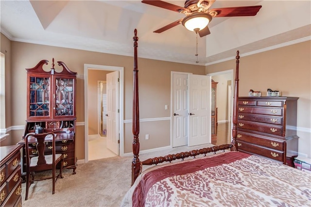 carpeted bedroom with ceiling fan, ensuite bath, ornamental molding, and a tray ceiling