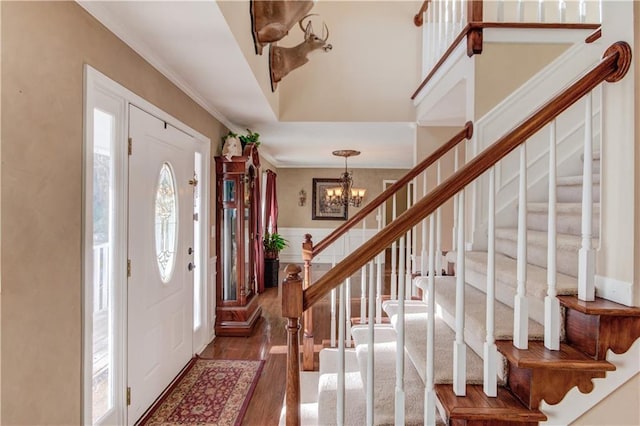 entryway with crown molding, dark hardwood / wood-style flooring, and a notable chandelier