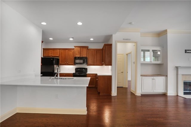 1585 Oak Meadows Ln, Cumming, GA 30041 - kitchen featuring black appliances, a peninsula, light countertops, brown cabinets, and dark wood-style floors
