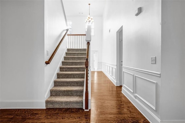 7601 Watson Cir, Locust Grove, GA 30248 - stairs featuring wood finished floors, a chandelier, a wainscoted wall, and a decorative wall