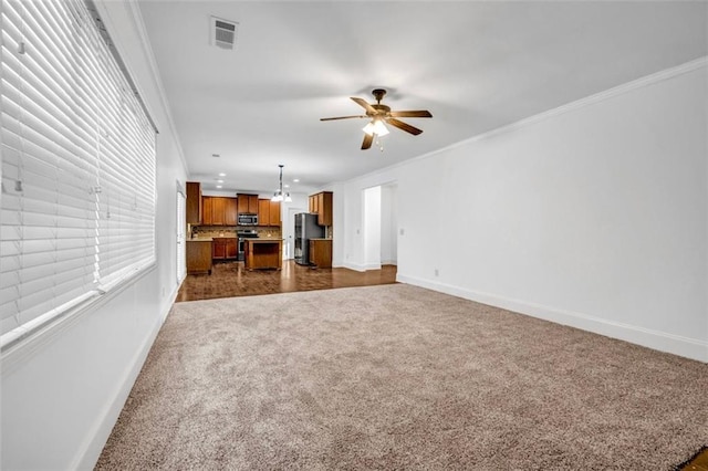 7601 Watson Cir, Locust Grove, GA 30248 - unfurnished living room featuring dark carpet, baseboards, a ceiling fan, crown molding, and a chandelier