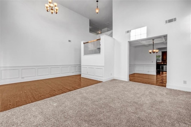 7601 Watson Cir, Locust Grove, GA 30248 - spare room with a chandelier, a towering ceiling, carpet, a decorative wall, and a wainscoted wall