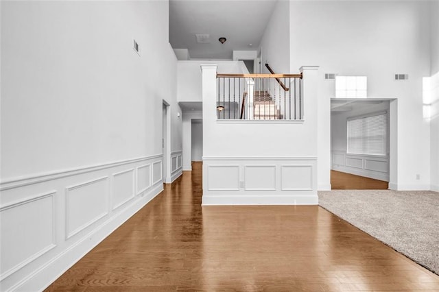 7601 Watson Cir, Locust Grove, GA 30248 - unfurnished living room featuring a high ceiling, a decorative wall, wood finished floors, and wainscoting