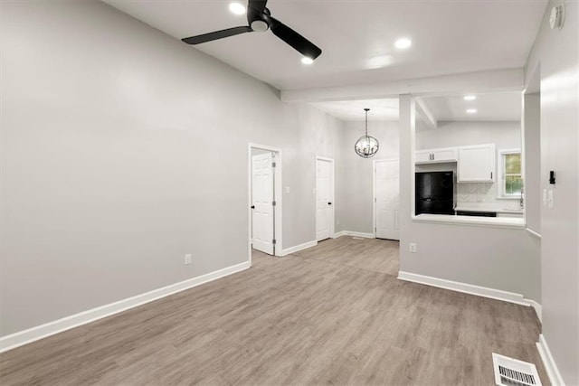 unfurnished living room with light wood-type flooring, vaulted ceiling with beams, and ceiling fan with notable chandelier