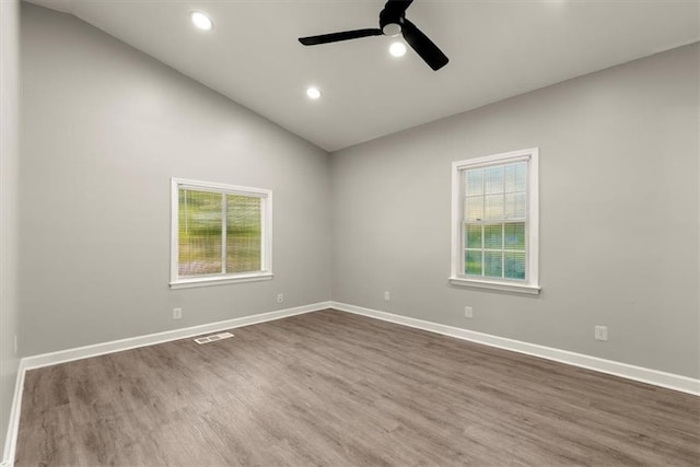 spare room featuring a healthy amount of sunlight, lofted ceiling, and dark hardwood / wood-style floors