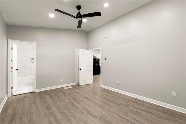 unfurnished bedroom with connected bathroom, hardwood / wood-style floors, high vaulted ceiling, and ceiling fan