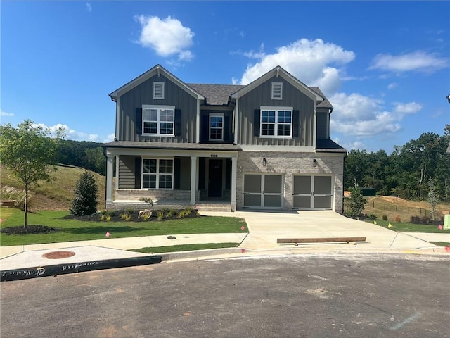 craftsman inspired home featuring a garage, covered porch, and a front yard