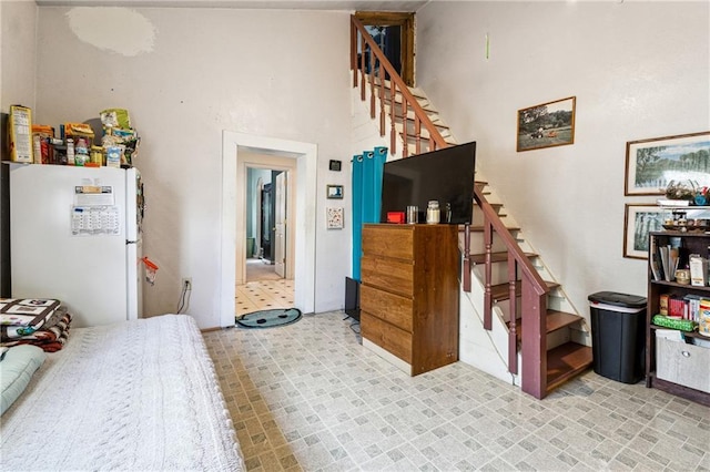 bedroom with a towering ceiling and freestanding refrigerator