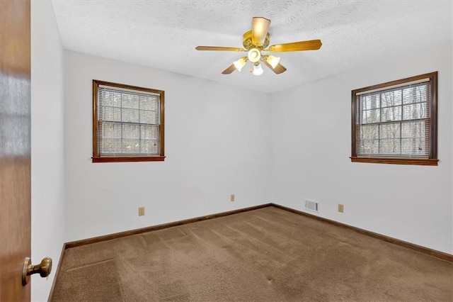 carpeted empty room featuring visible vents, a textured ceiling, baseboards, and a ceiling fan