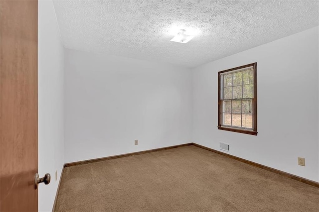 spare room featuring visible vents, carpet flooring, a textured ceiling, and baseboards