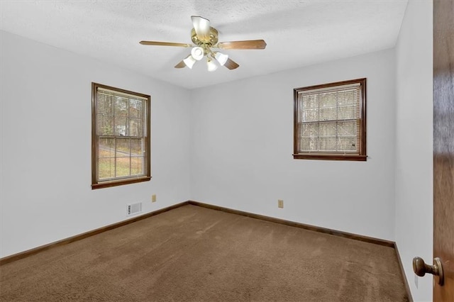 spare room with visible vents, a textured ceiling, a healthy amount of sunlight, and carpet flooring