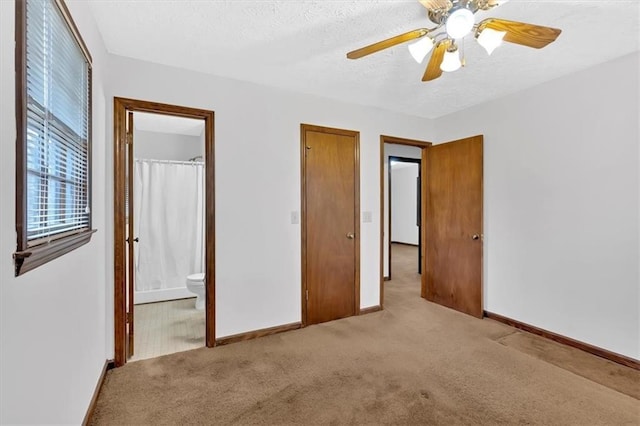 unfurnished bedroom with a ceiling fan, a textured ceiling, ensuite bath, carpet floors, and baseboards