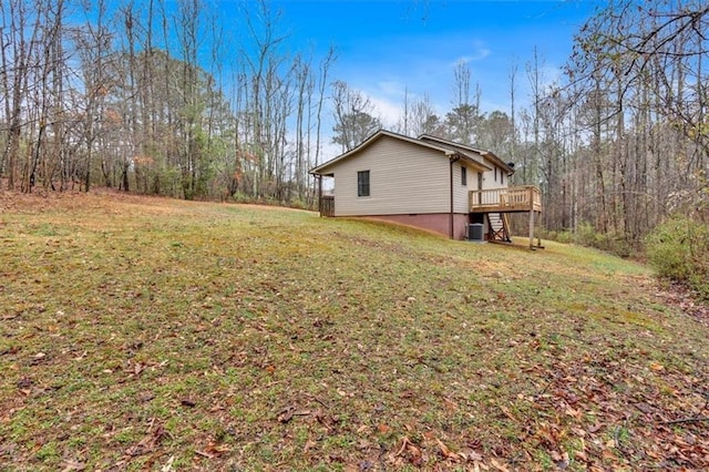 view of side of home featuring a deck, central AC unit, a lawn, and a forest view