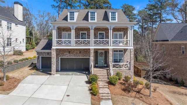 view of front of house with a balcony, a porch, an attached garage, concrete driveway, and brick siding