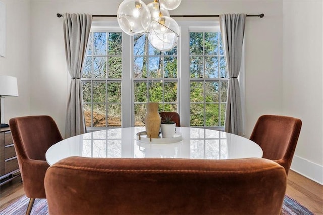 dining area featuring a notable chandelier, wood finished floors, and baseboards