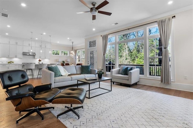 living area featuring recessed lighting, visible vents, ornamental molding, and wood finished floors