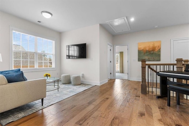 living area featuring hardwood / wood-style floors, attic access, baseboards, and visible vents