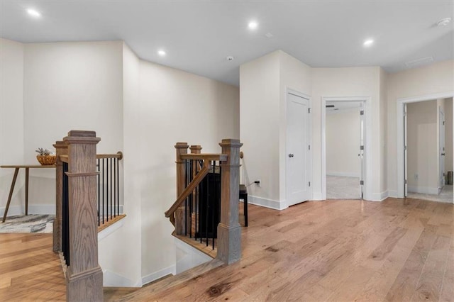 hall featuring wood finished floors, recessed lighting, an upstairs landing, and baseboards