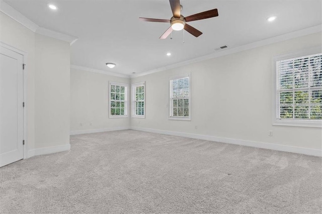 unfurnished room with a wealth of natural light, visible vents, carpet floors, and ornamental molding