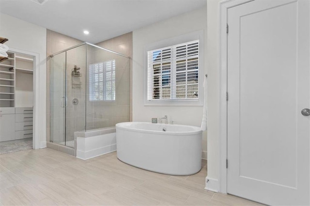 full bath with recessed lighting, a freestanding bath, a spacious closet, and a shower stall