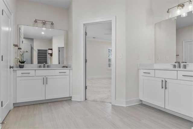 full bathroom featuring two vanities, baseboards, and a sink