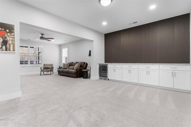 living area with visible vents, wooden walls, beverage cooler, light colored carpet, and a bar