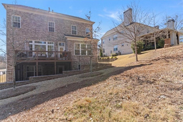 back of property featuring a wooden deck and brick siding