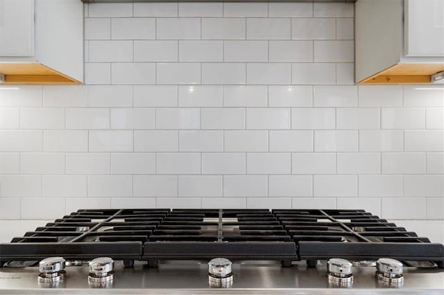 room details with decorative backsplash, light countertops, and stainless steel gas stovetop