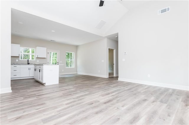 121 Hunters Ln, Powder Springs, GA 30127 - unfurnished living room featuring baseboards, light wood-type flooring, visible vents, high vaulted ceiling, and a sink