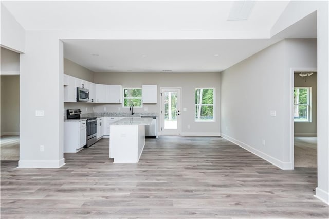 121 Hunters Ln, Powder Springs, GA 30127 - kitchen with white cabinetry, a kitchen island, stainless steel appliances, open floor plan, and baseboards