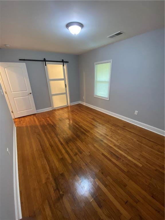 2319 Beecher Rd SW, Atlanta, GA 30311 - unfurnished bedroom featuring dark wood-style floors, a barn door, and baseboards