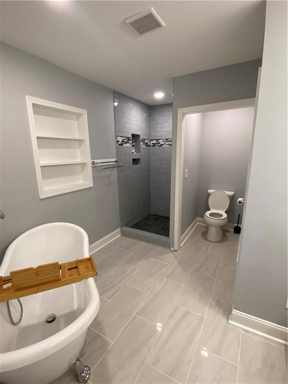 2319 Beecher Rd SW, Atlanta, GA 30311 - bathroom featuring built in features, tiled shower, a freestanding bath, baseboards, and toilet
