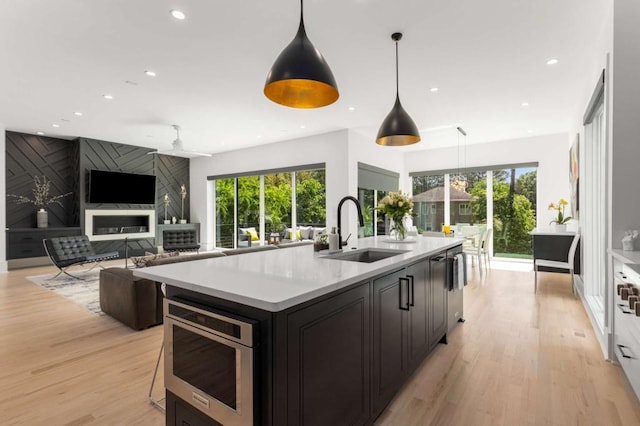 kitchen with a sink, light countertops, light wood-type flooring, recessed lighting, and an island with sink
