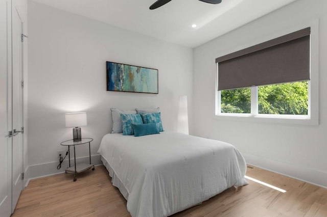 bedroom with light wood-style flooring, baseboards, and a ceiling fan