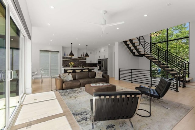 living room with stairs, recessed lighting, light wood finished floors, and a ceiling fan