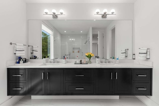bathroom with marble finish floors, double vanity, a shower stall, and baseboards